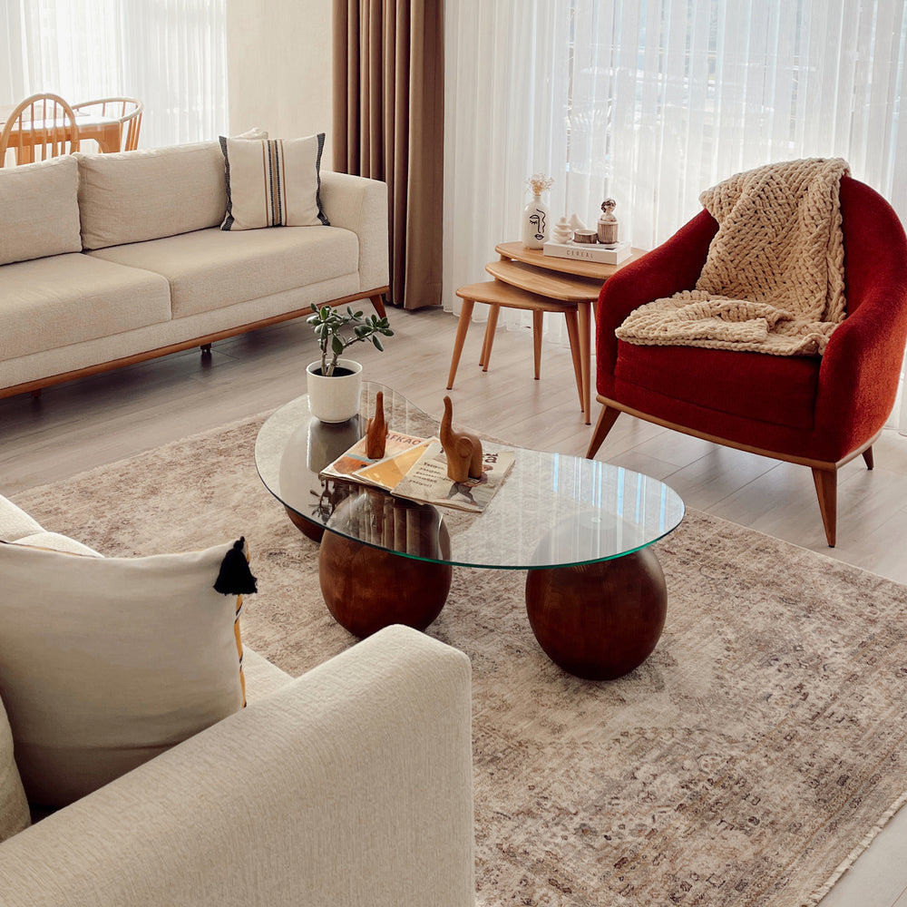 Modern living room with beige sofa, red armchair, and glass coffee table.