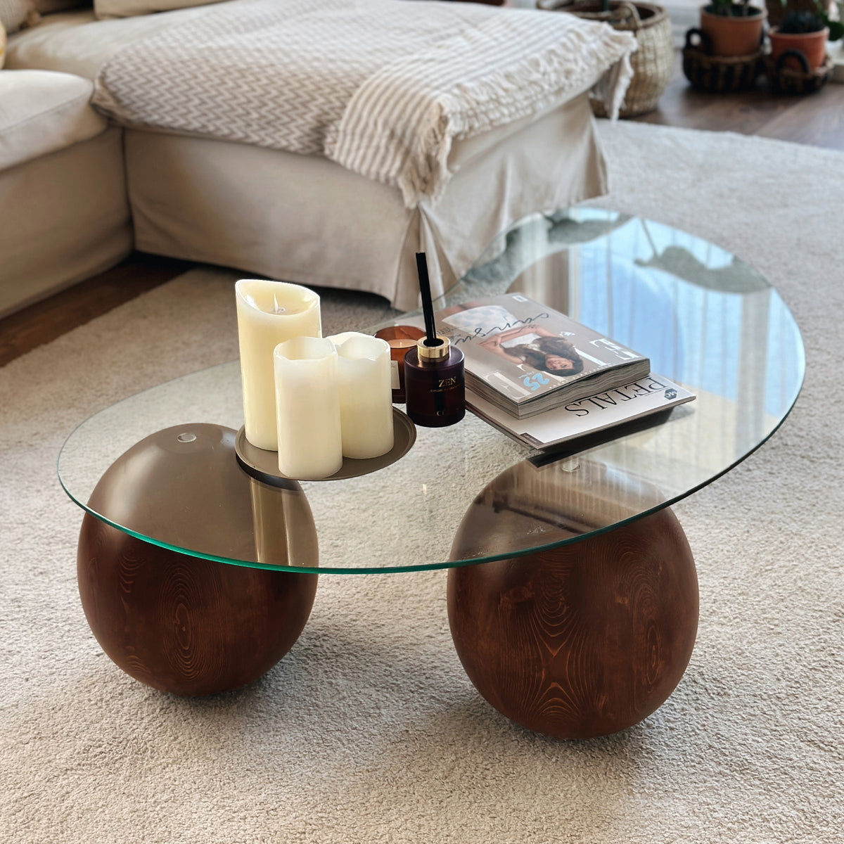 Close-up of the curved glass top and two large round wooden ball legs of the coffee table