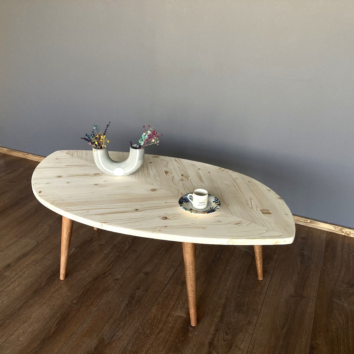 Leaf shaped coffee table with a pale natural wood top and light legs on a wood floor