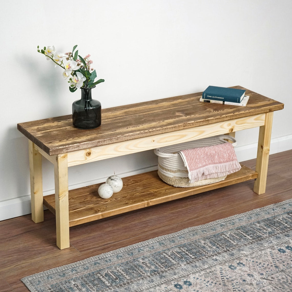 Entryway bench seen from the right with a vase of white flowers and a book on top of the seat