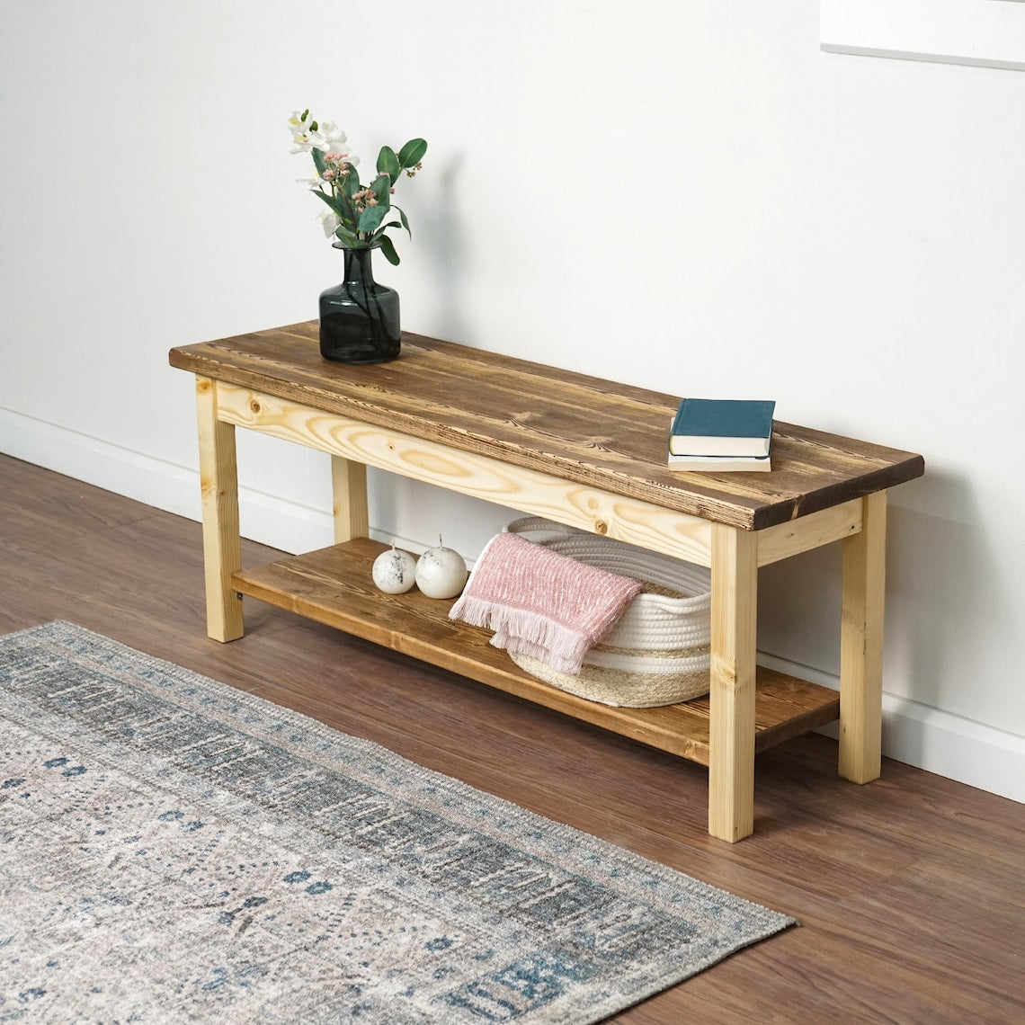 Entryway bench with a dark top and light legs from the left, a woven basket on the lower shelf