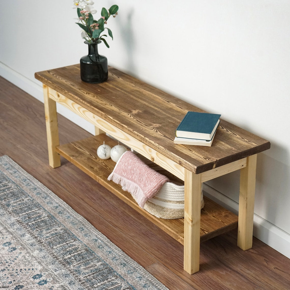 Entryway bench with a lower shelf from a high left angle, with decorative balls and a basket on the shelf