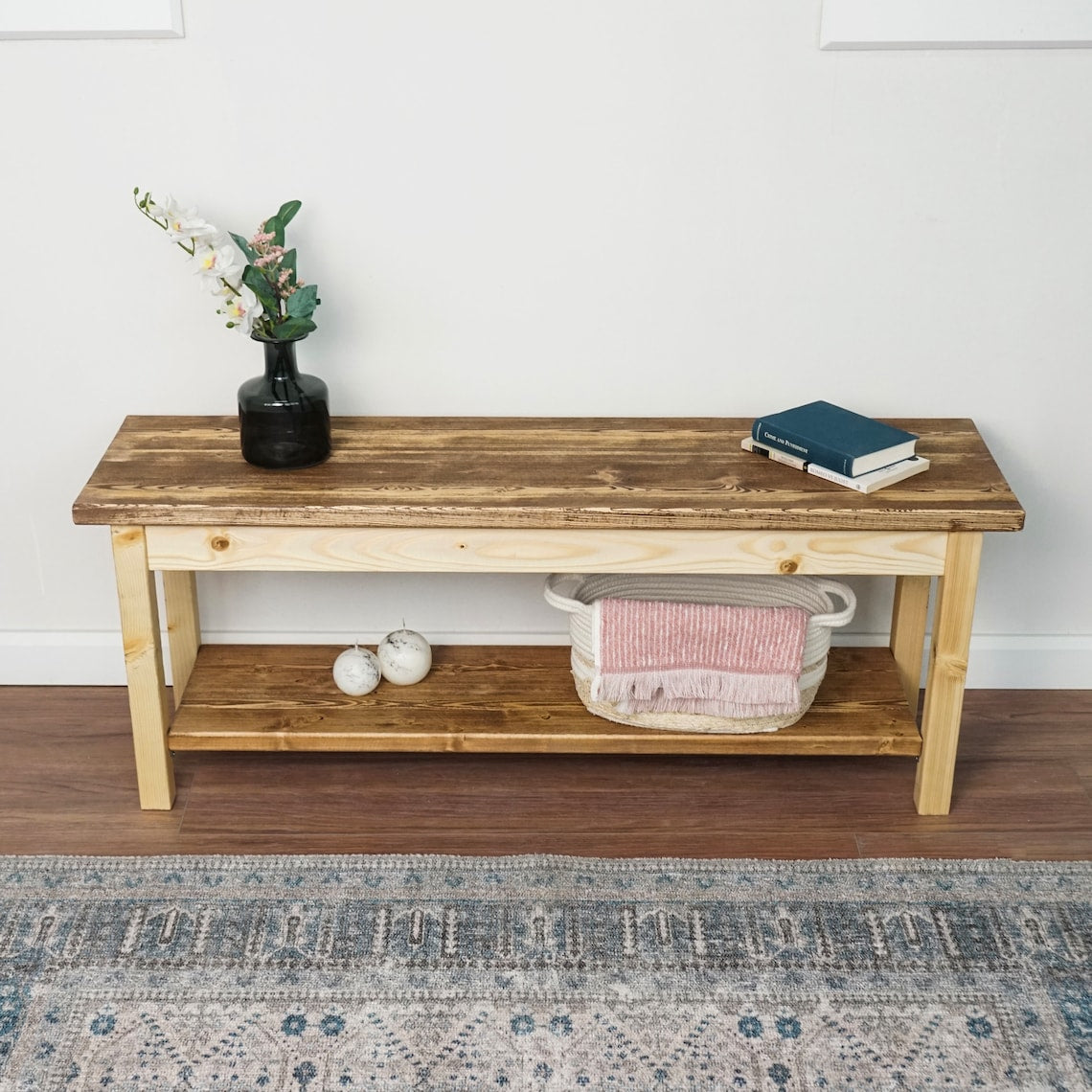 Front view of the spruce entryway bench with a dark top and a lower shoe shelf holding a basket