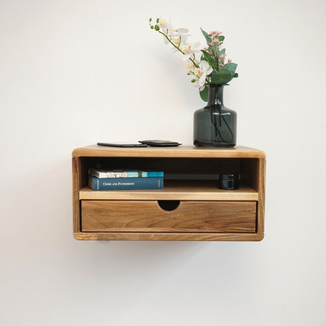 Front view of the walnut floating nightstand with open shelf and drawer on a plain white wall
