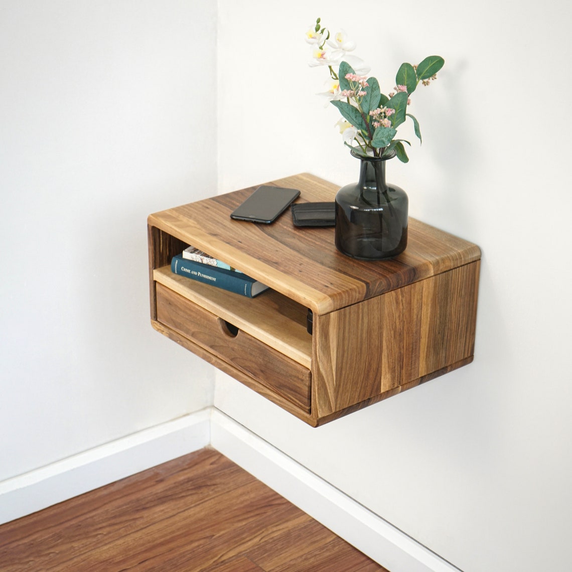 Floating walnut nightstand mounted in a wall corner, angled view of the open shelf and drawer