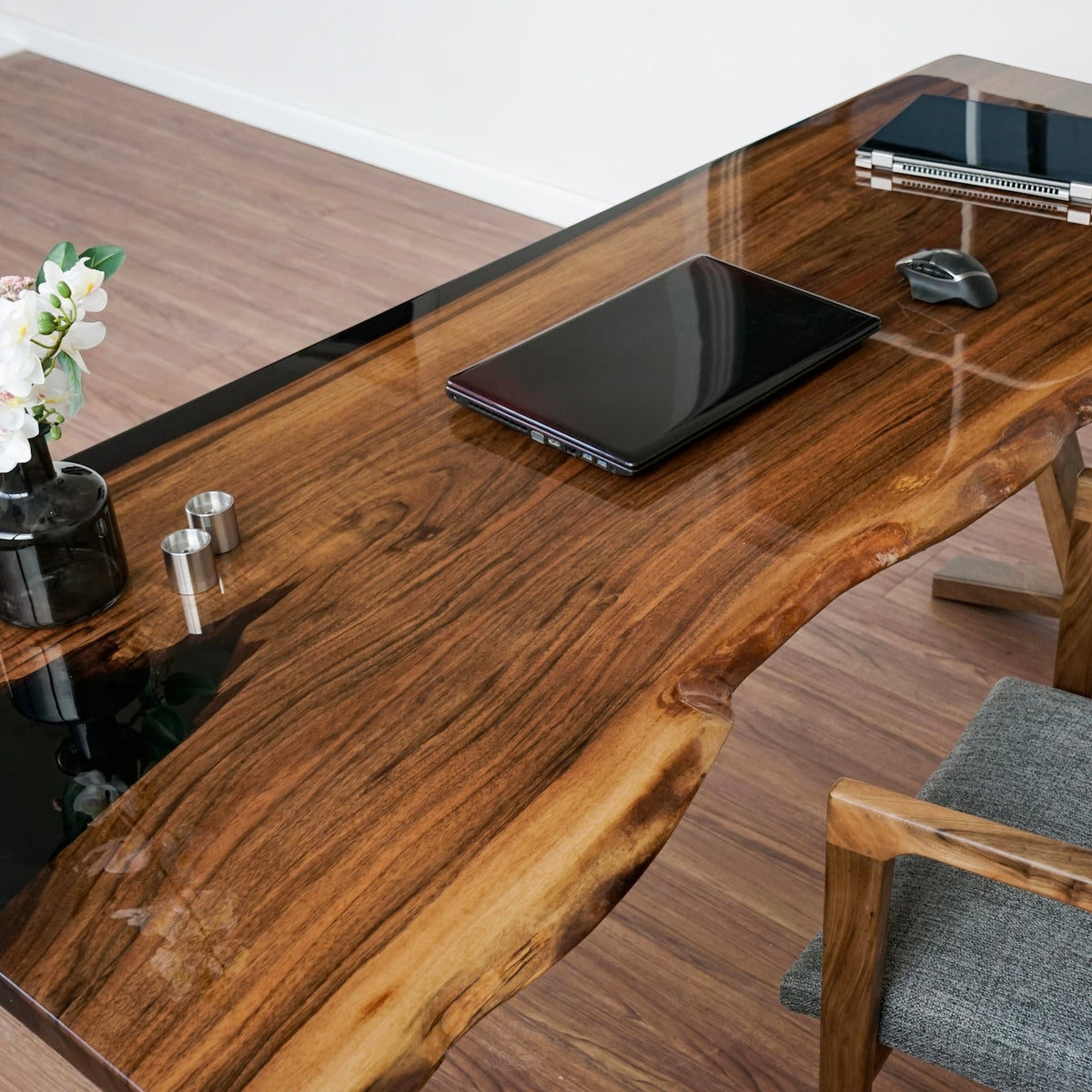 Top view of the live edge walnut desk surface with glossy epoxy and a laptop on it