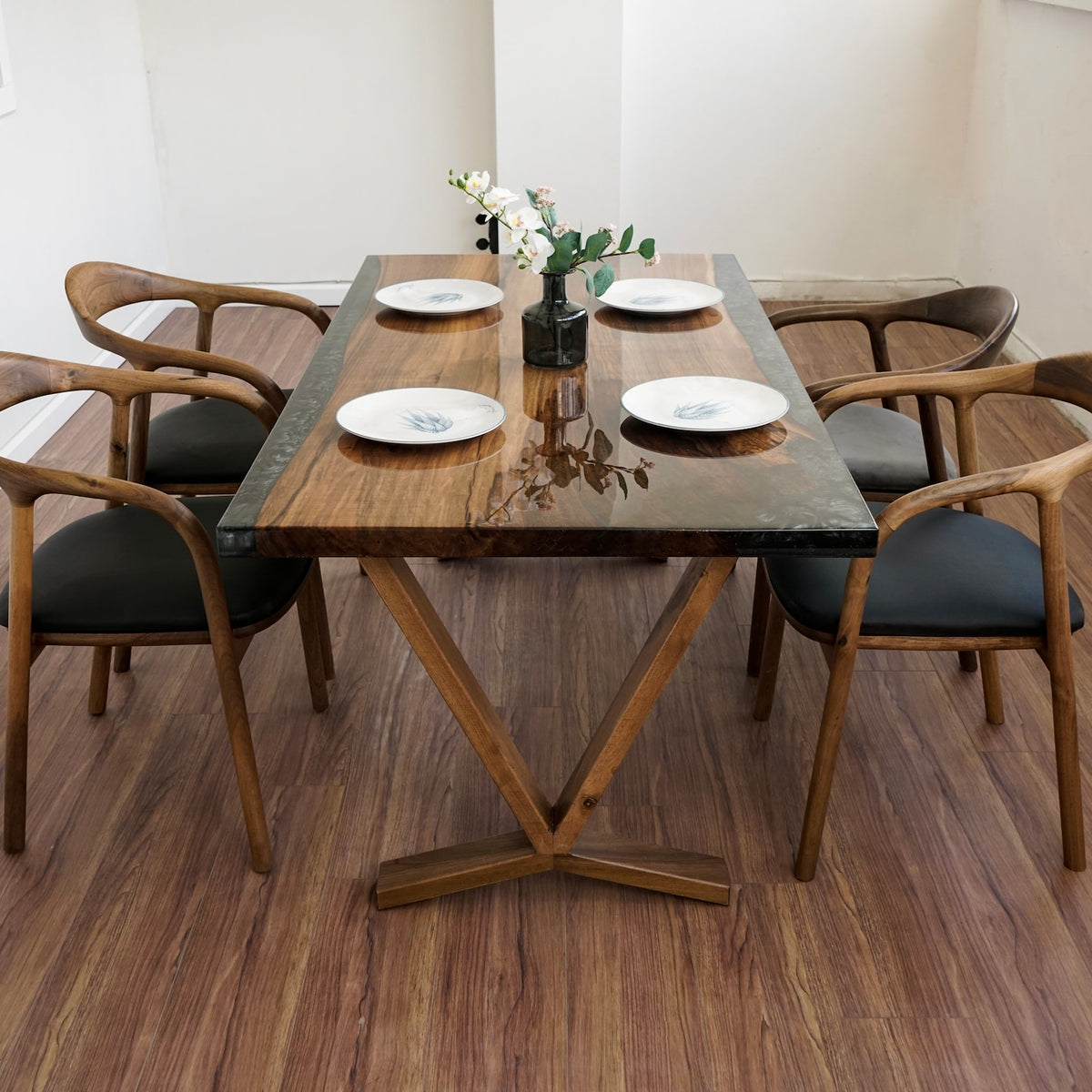 Front view of the walnut dining table with a dark epoxy seam down the center, on V legs with a Y-shaped foot