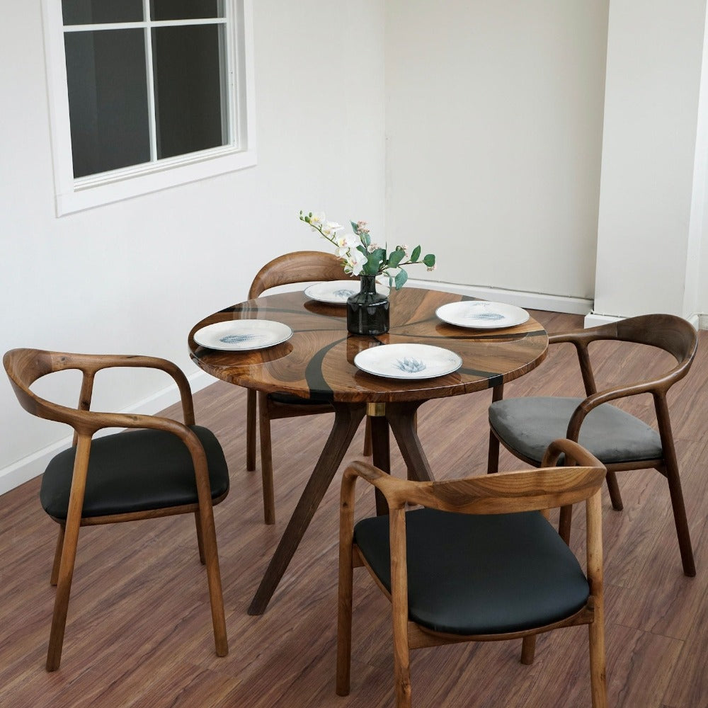 Round walnut dining table with black epoxy swirl and wooden tripod legs, with three wooden armchairs