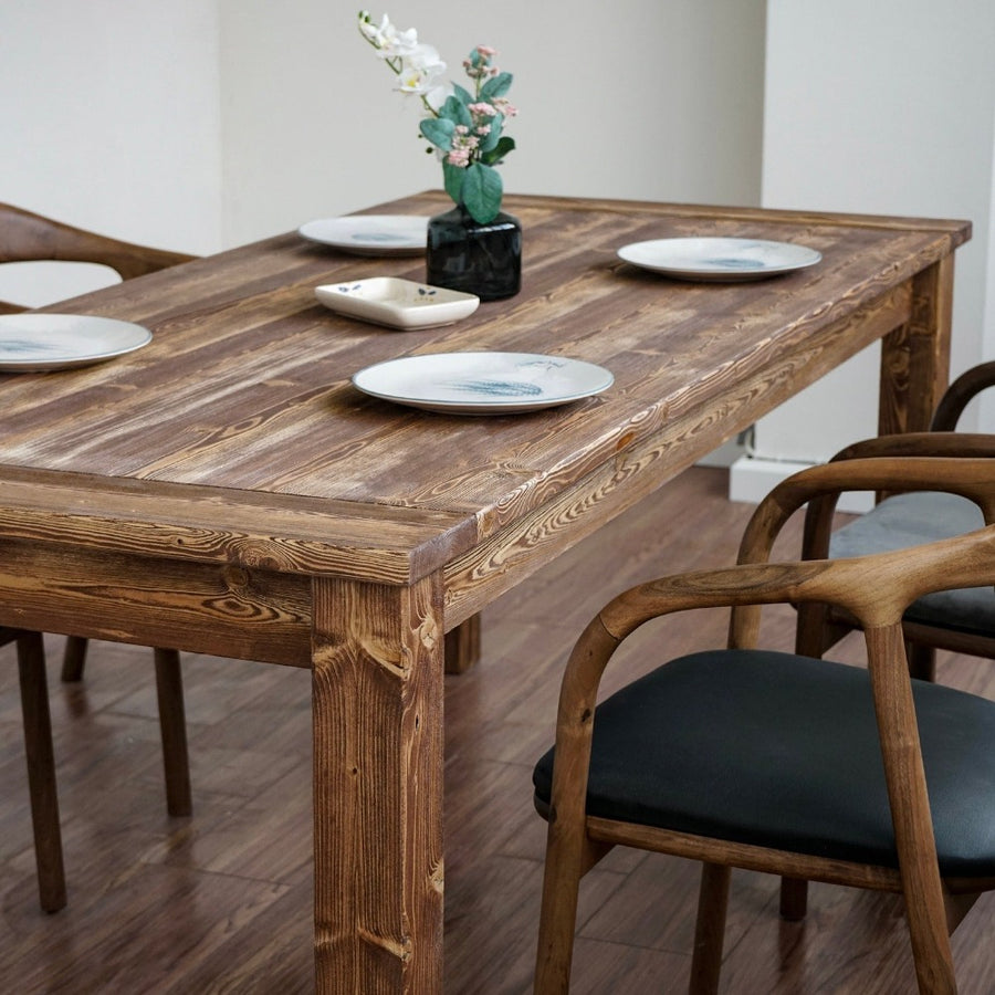 Close-up of the Parson spruce farmhouse dining table top and thick leg with plates and a vase of flowers