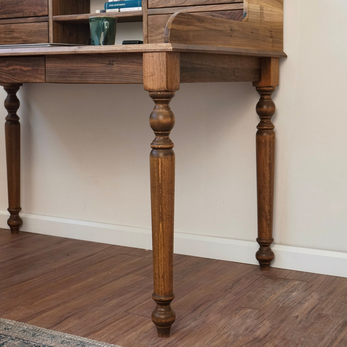 Side view of the turned walnut desk leg and the underside of the desktop edge