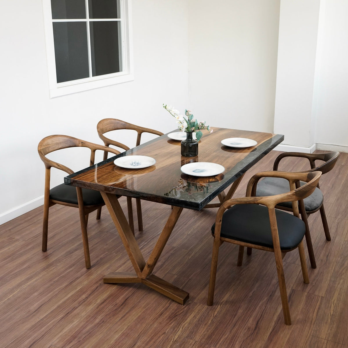 Walnut epoxy dining table from a corner angle with four armchairs around it in a white room