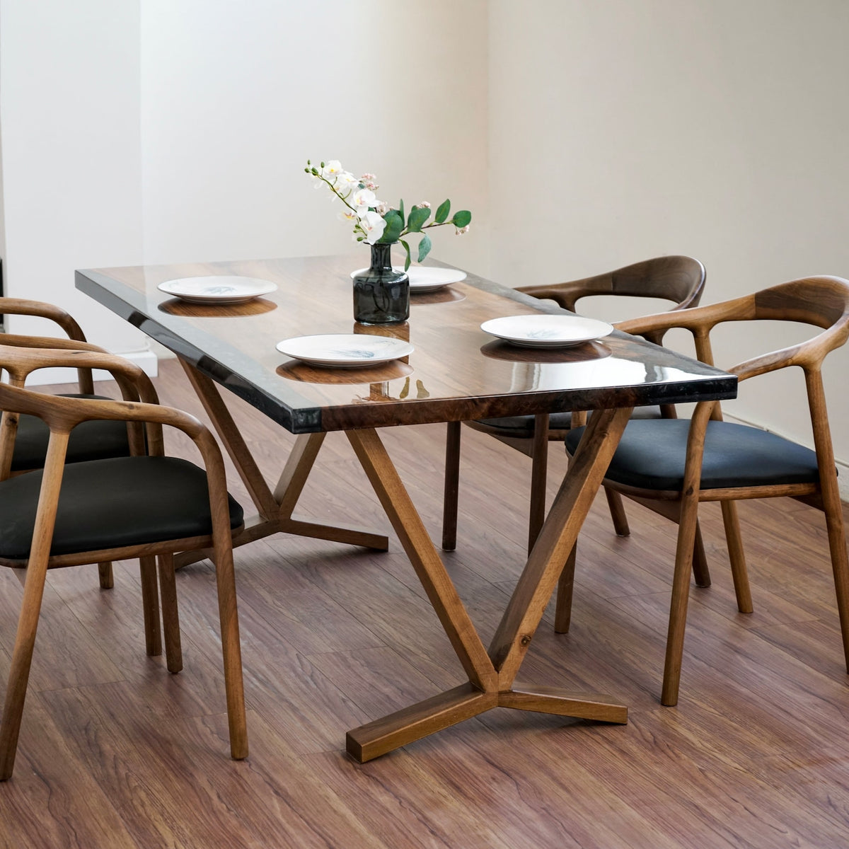 Walnut epoxy dining table angled from the left, wooden armchairs on both long sides