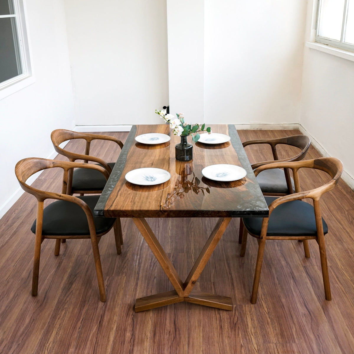 High angle of the walnut dining table with a dark epoxy strip along each edge and four armchairs