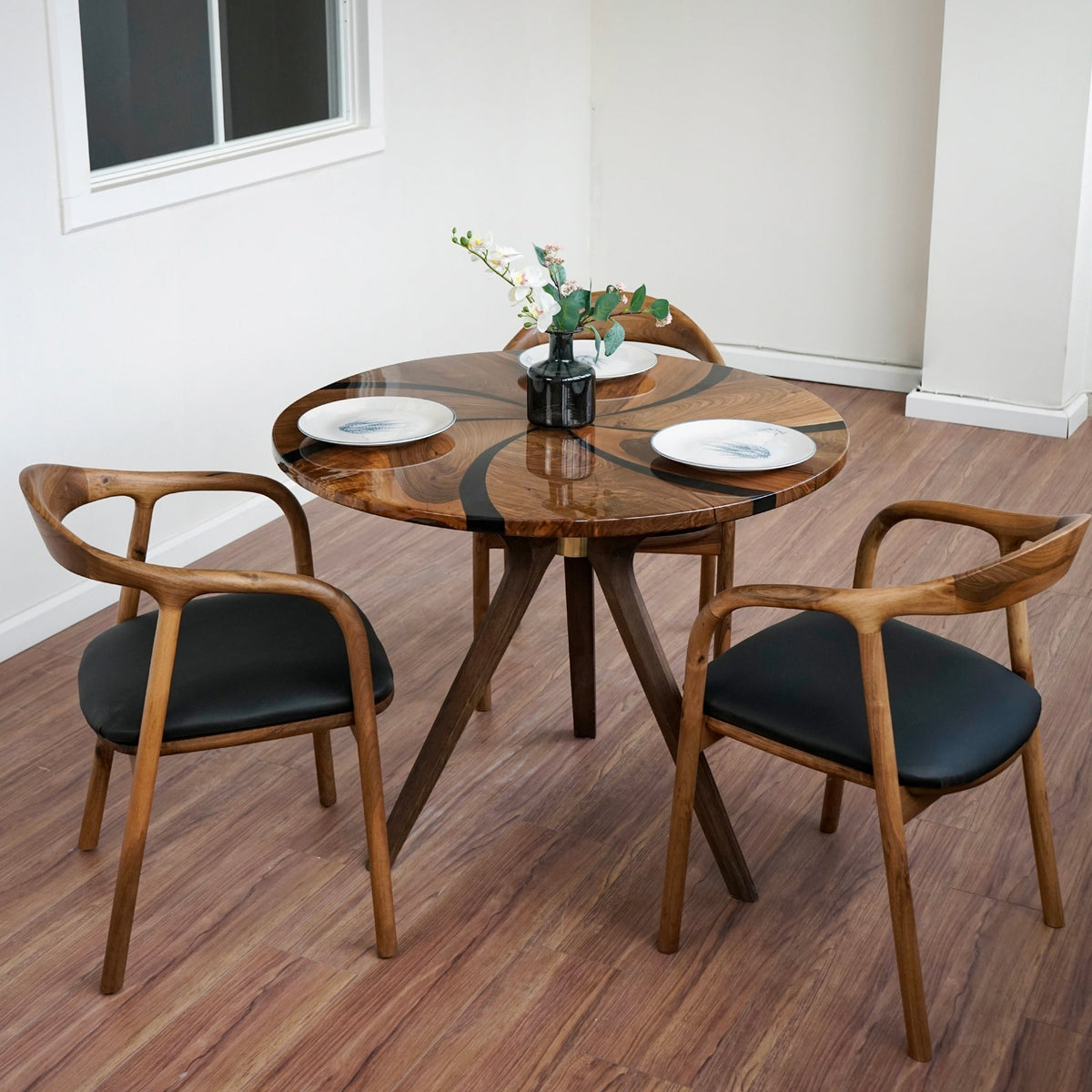 Walnut dining table with black epoxy swirl and wooden legs, angled view from a corner of the room
