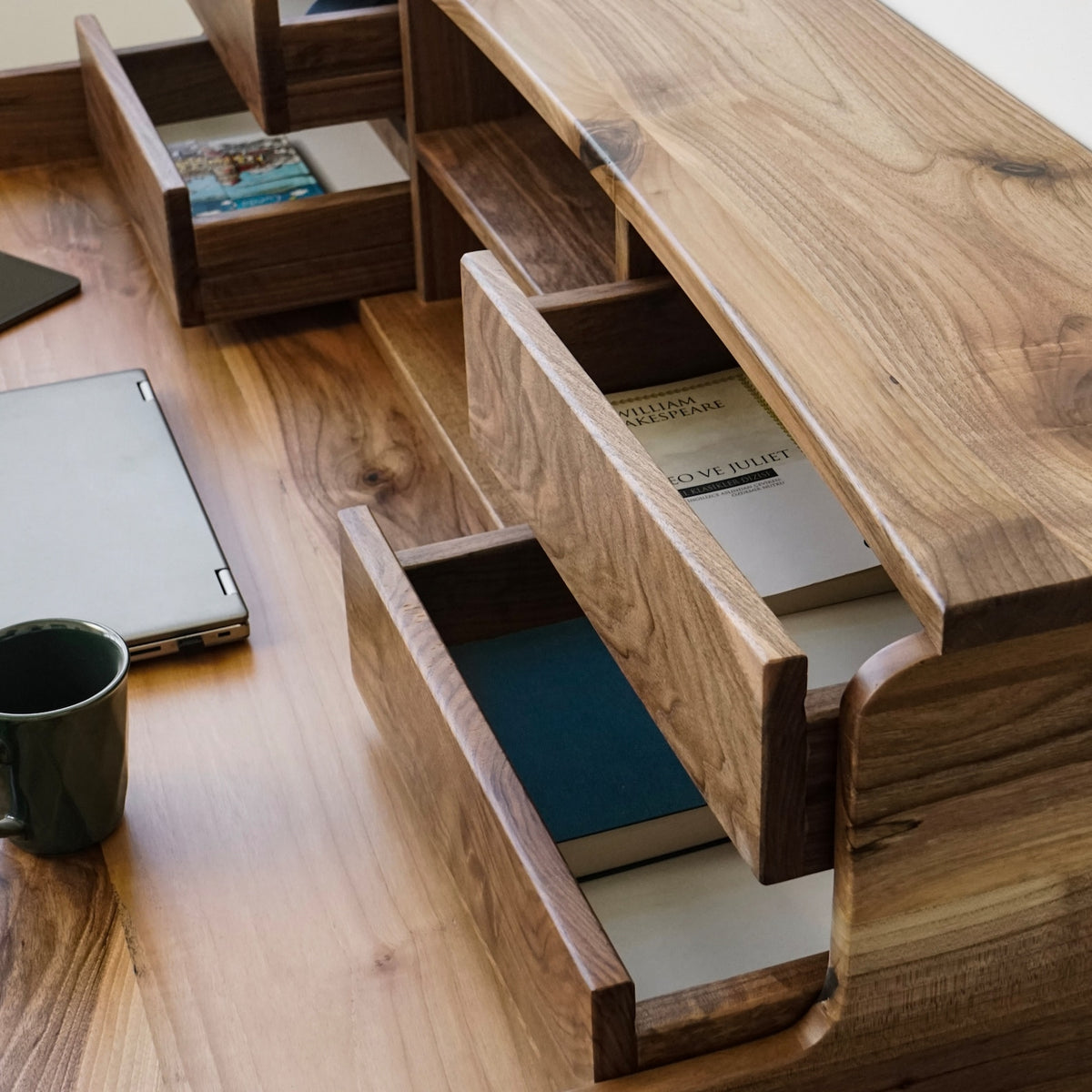 Walnut desk hutch drawers pulled open, showing the inside of the drawers and a book