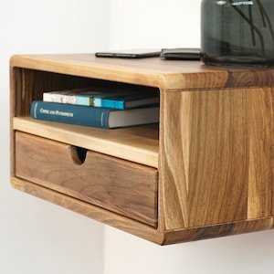 Side-angle close-up of the walnut floating nightstand with books on the open shelf