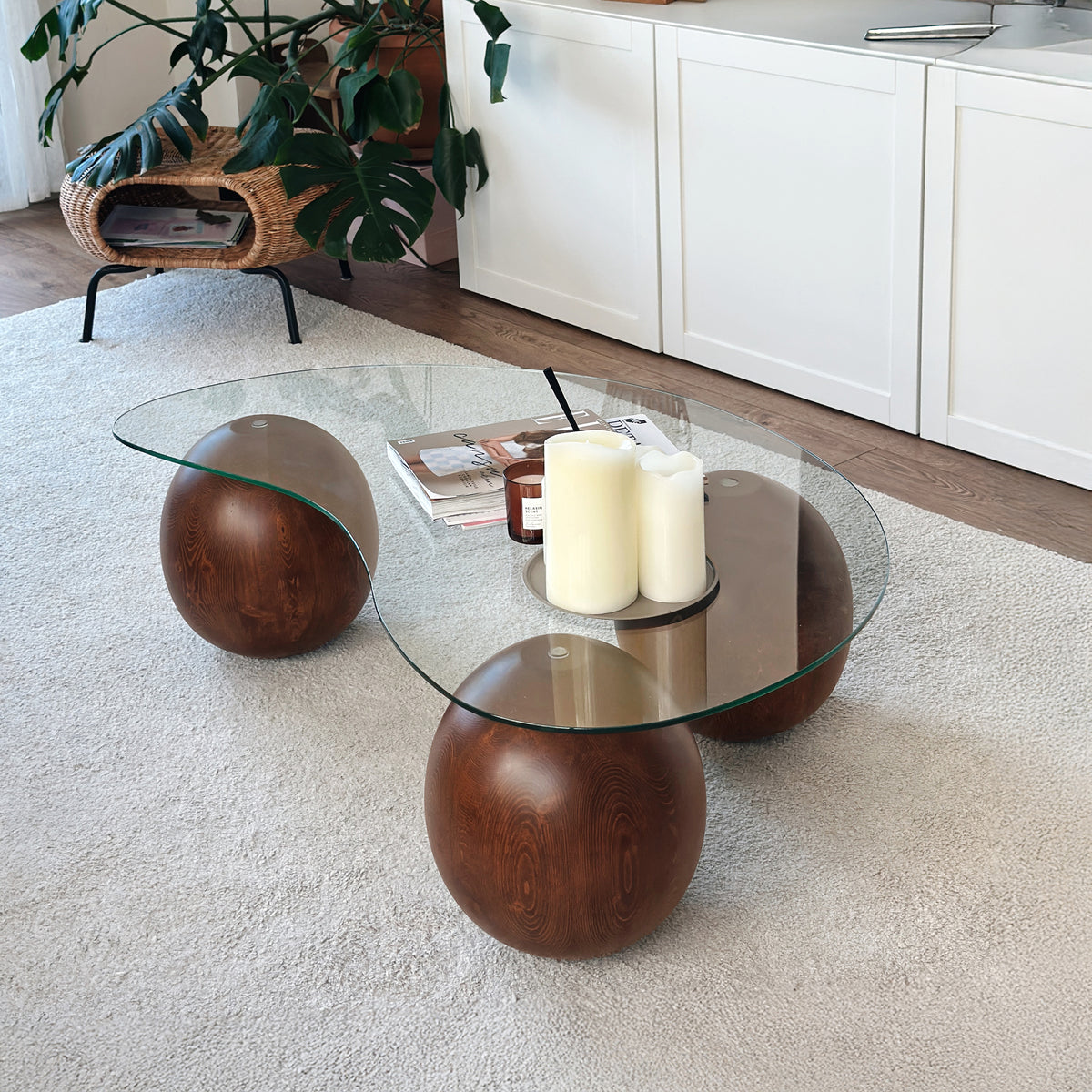 Top-front view of the glass coffee table on its wooden ball legs over a cream rug