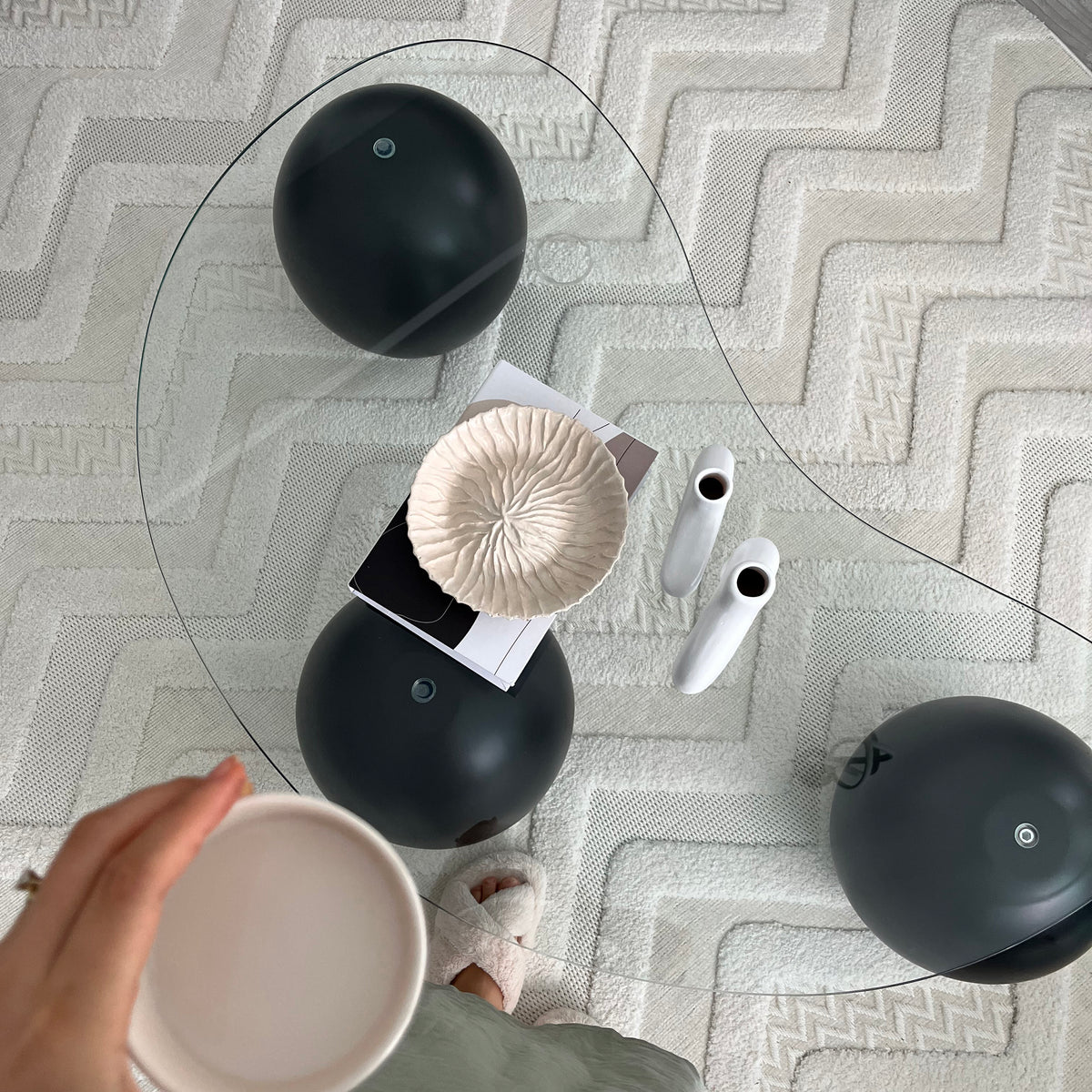 Top-down view through the glass top showing the black ball legs on a white textured rug