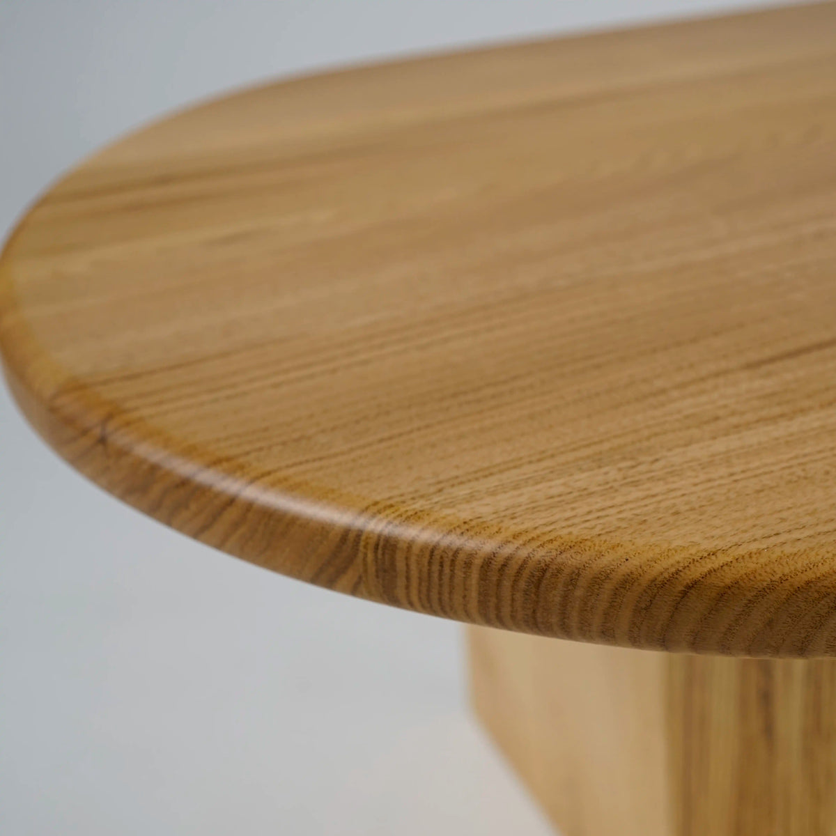 Close-up of the smooth oval top and rounded edge of the chestnut wood coffee table