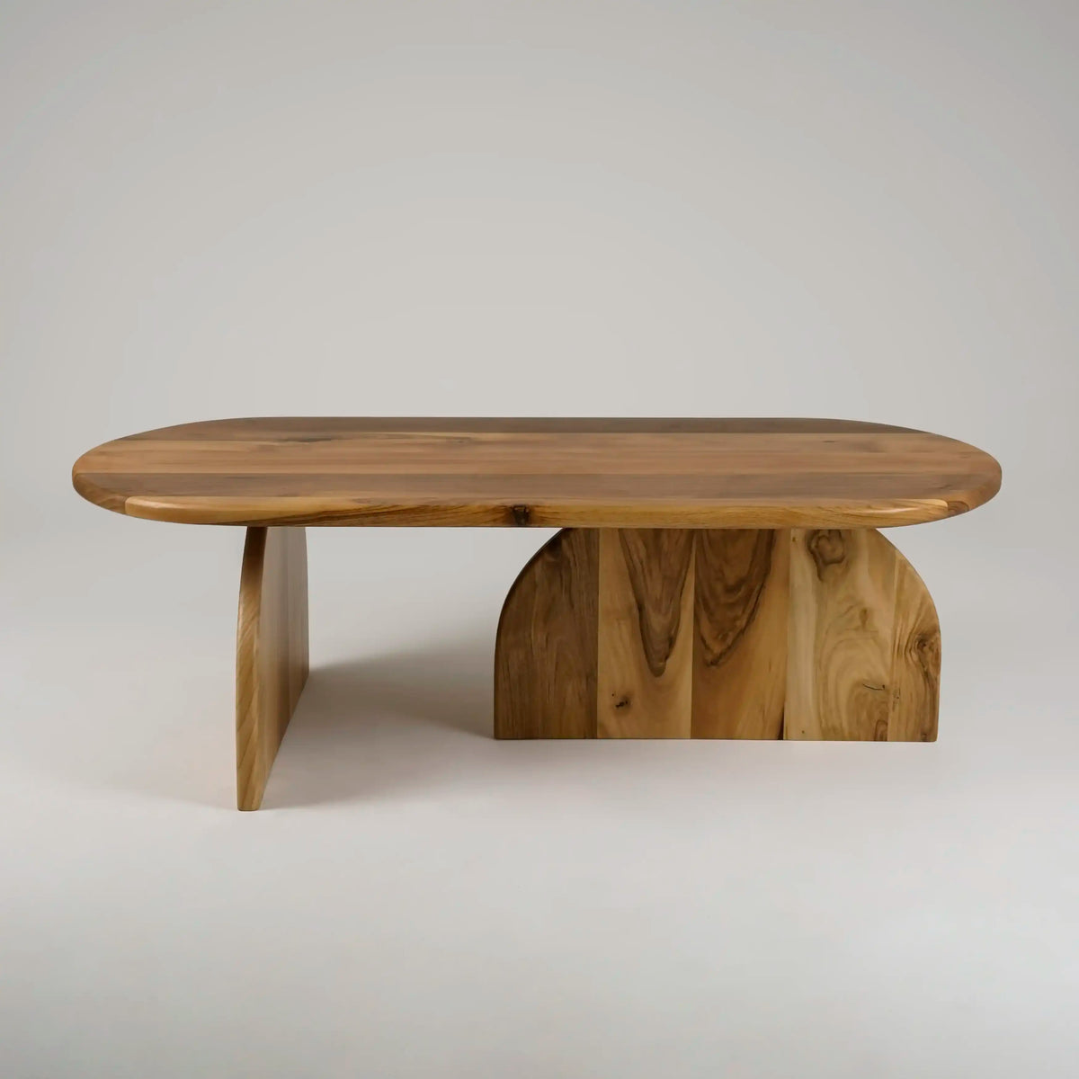 Walnut Japandi oval coffee table with two half-round feet, front view on a gray backdrop