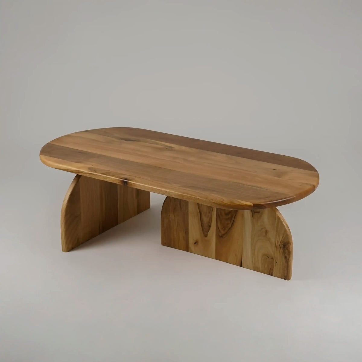 Walnut oval coffee table with half-round feet seen from a high angle on a gray backdrop