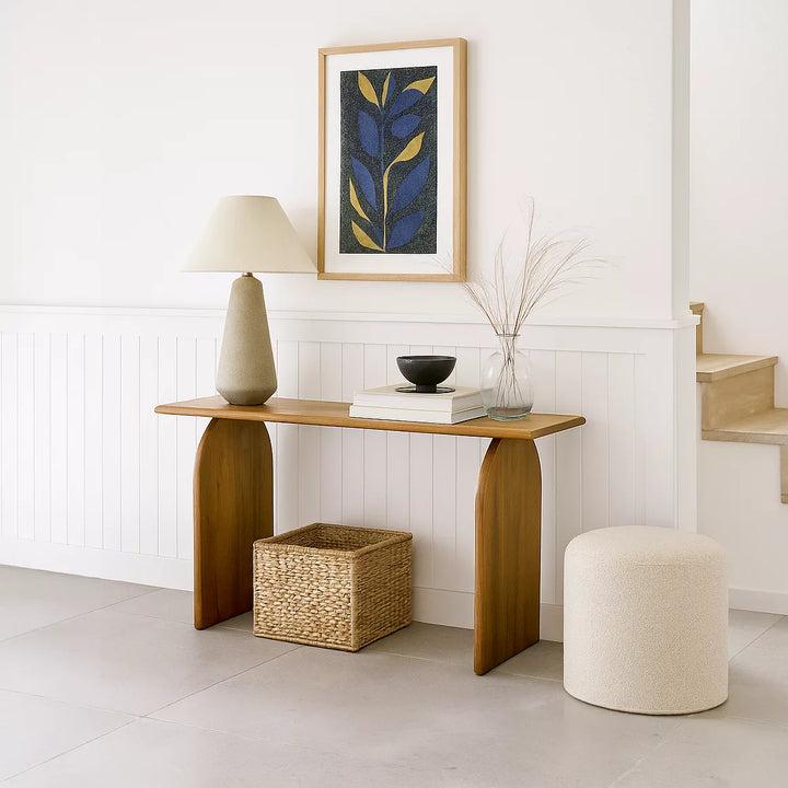 A minimalist white room with a wooden Japandi console table and a lamp, creating a serene atmosphere.
