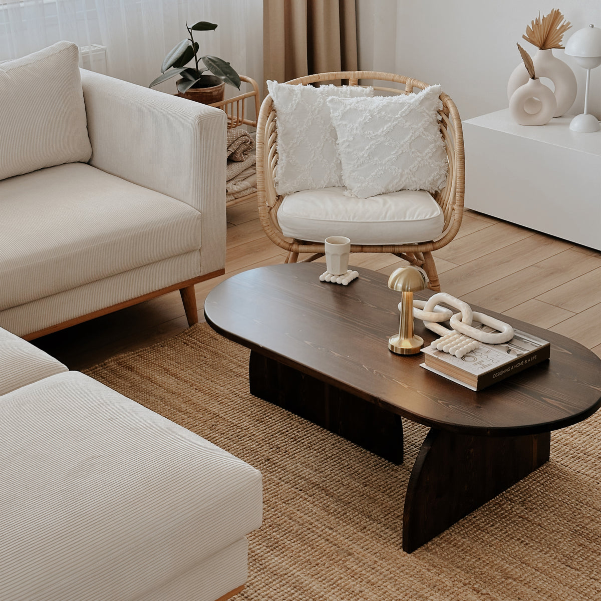 Dark brown solid wood Japandi coffee table with a sofa and wicker chair, three-quarter view