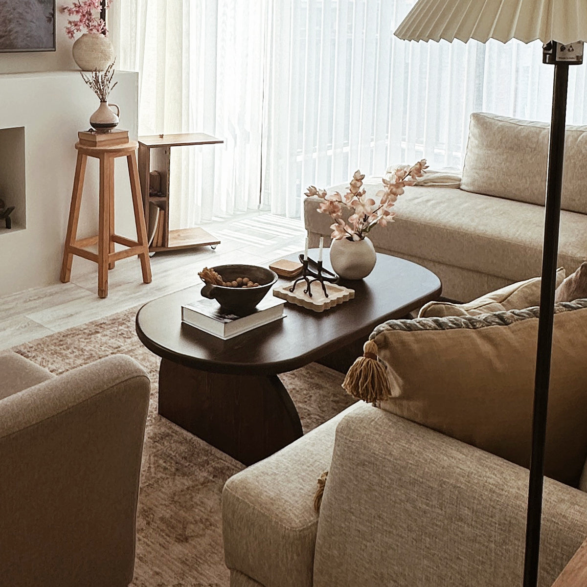Oval Japandi coffee table in a living room with beige sofas, seen from a raised angle