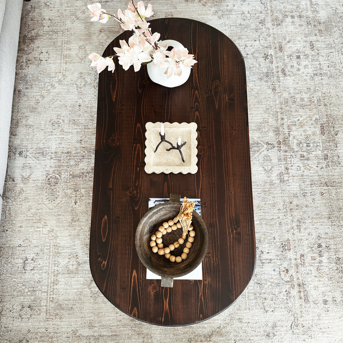 Top view of the dark brown oval Japandi coffee table on a patterned rug