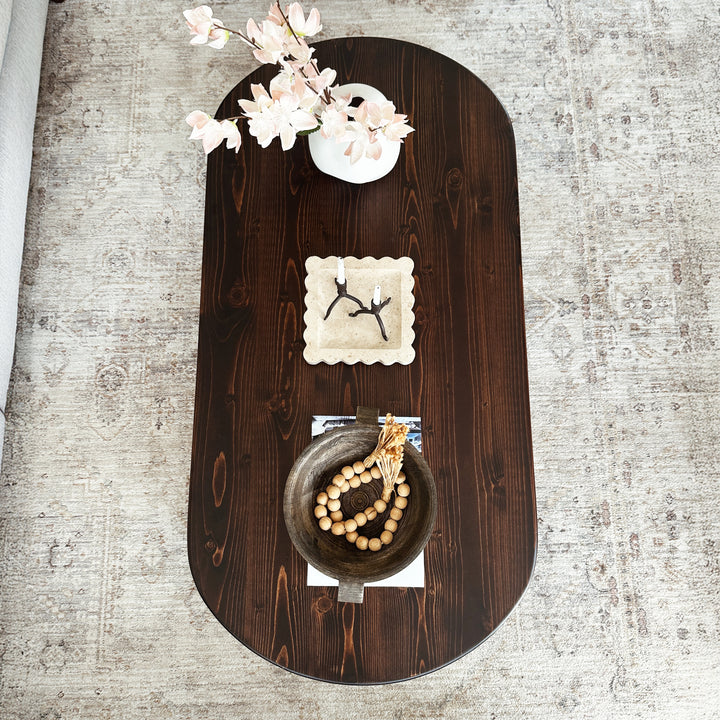 Decorative wall shelf with wooden finish holding a small plant, decorative plate, and beads on a textured wall background.