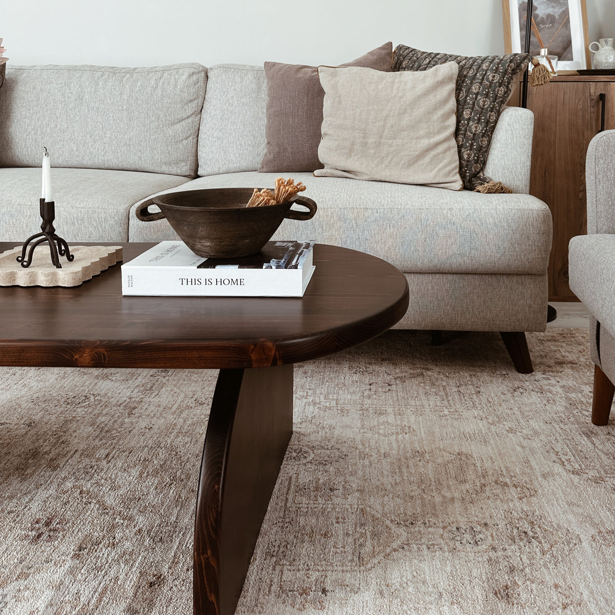 Side view of the Japandi coffee table half-round support with a gray sofa behind