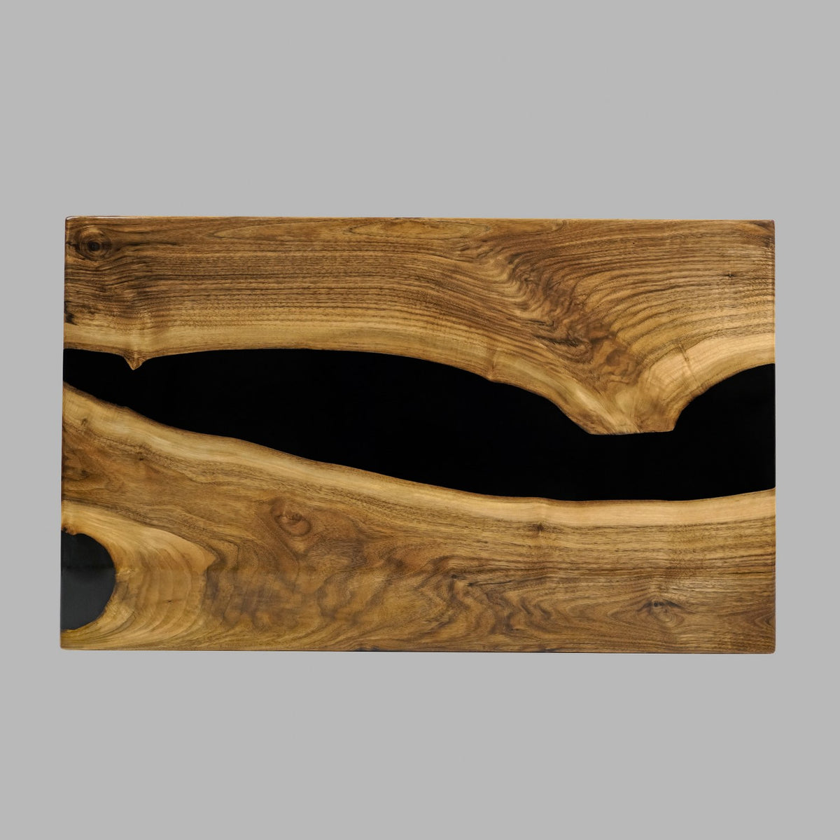 Top view of the walnut live edge coffee table top with a black epoxy river on a gray backdrop