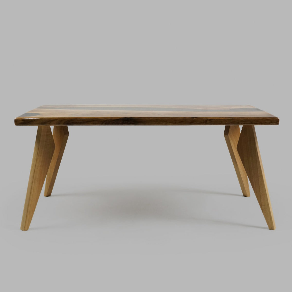 Side view of the live edge walnut coffee table on angled tapered legs, gray backdrop