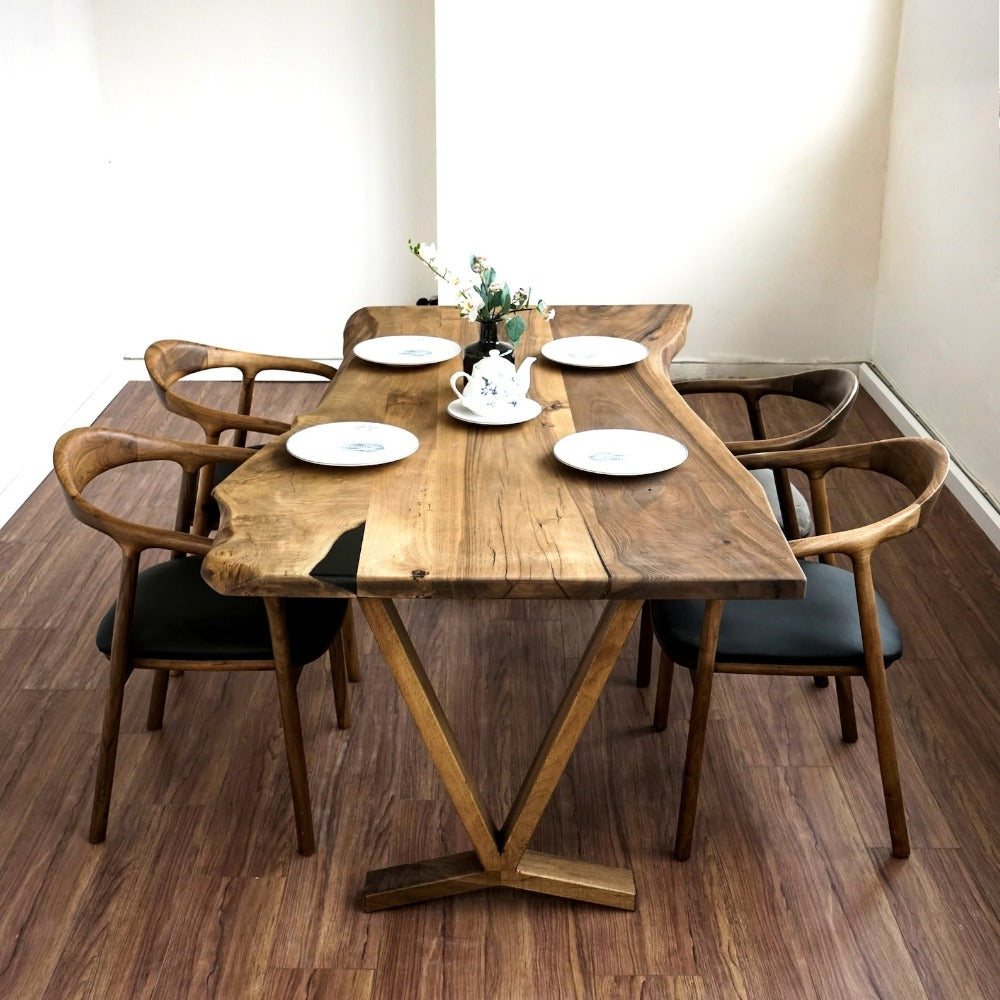 Walnut live edge farmhouse table, front view with a V-shaped wooden base and four chairs on a wood floor
