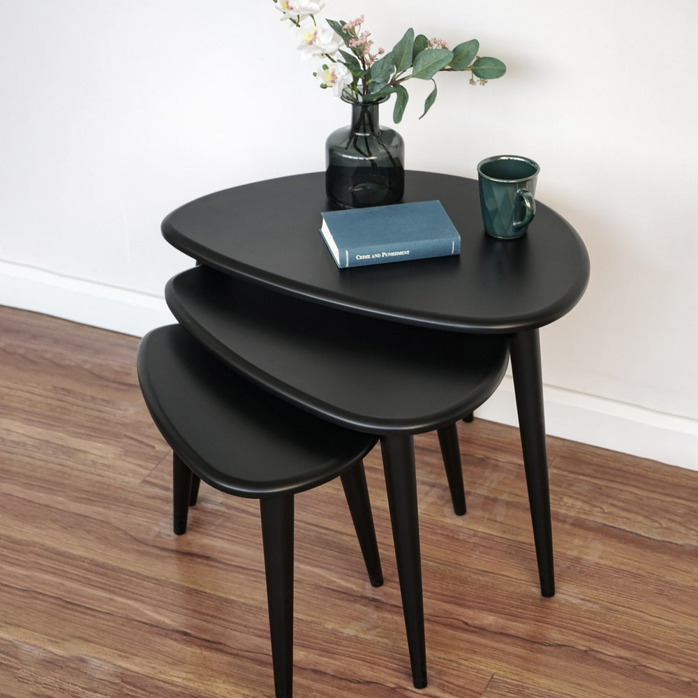 Matte black nesting tables fanned out from a high angle, showing three rounded triangular tops
