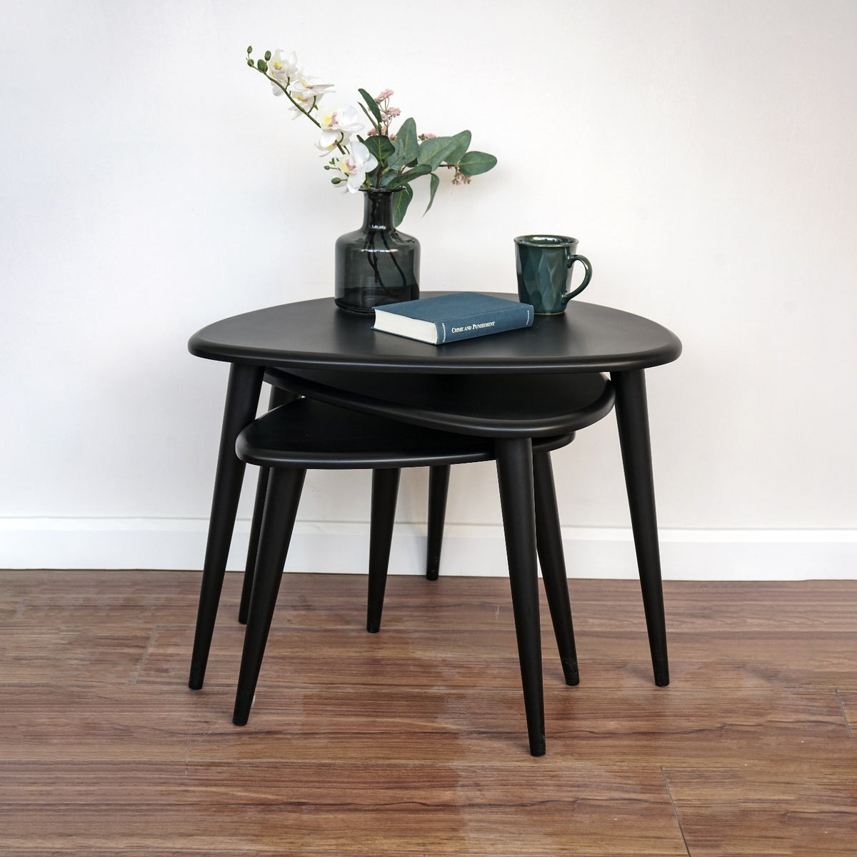 Matte black nesting tables nested tightly, front view with the legs of all three tables visible
