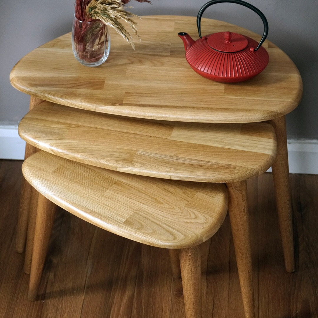 Close-up of the stacked natural oak pebble table tops showing the oak grain, with a red teapot