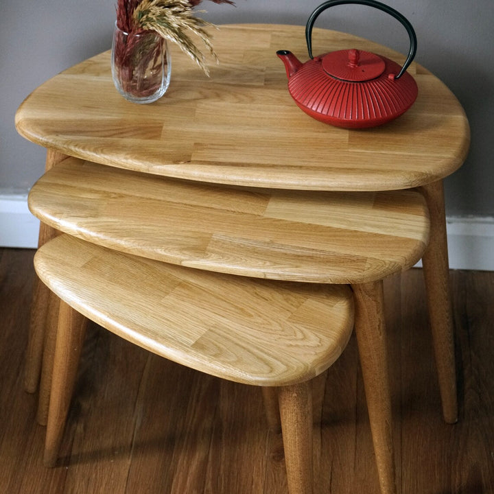 Close-up of the stacked natural oak pebble table tops showing the oak grain, with a red teapot
