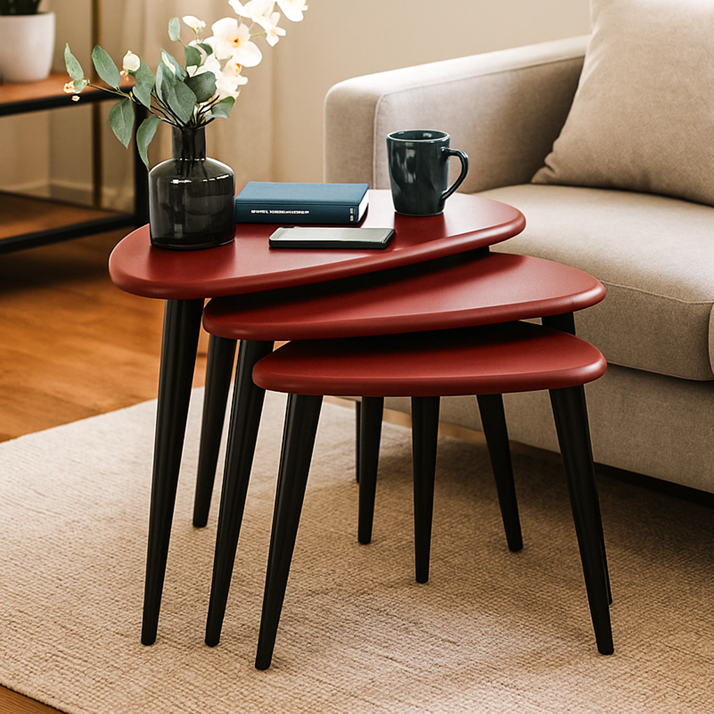 Set of three burgundy pebble nesting tables with black tapered legs, side view next to a sofa
