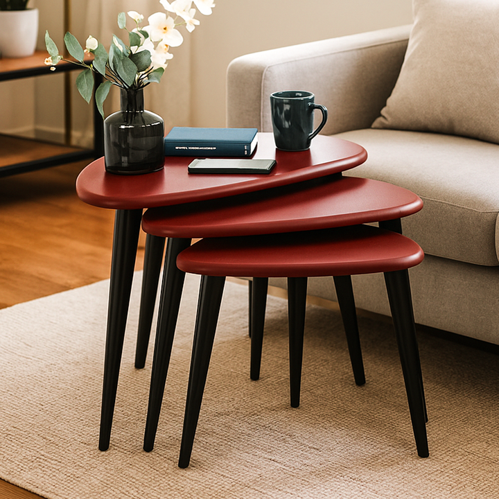 Set of three red nesting tables with a cup, book, and vase on top in a living room setting.
