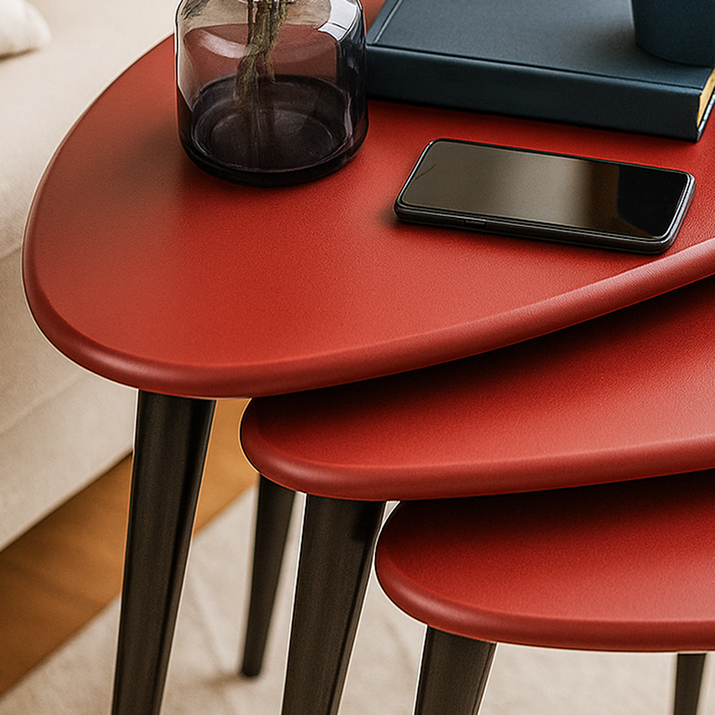 Close-up of the burgundy pebble nesting table tops and black legs, with a phone on the top table