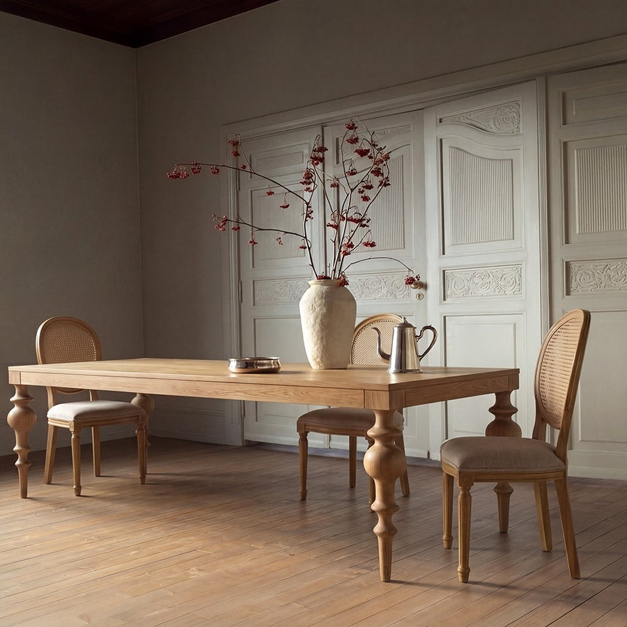 Normandy red oak dining table with cane back chairs and a stoneware vase of berry branches