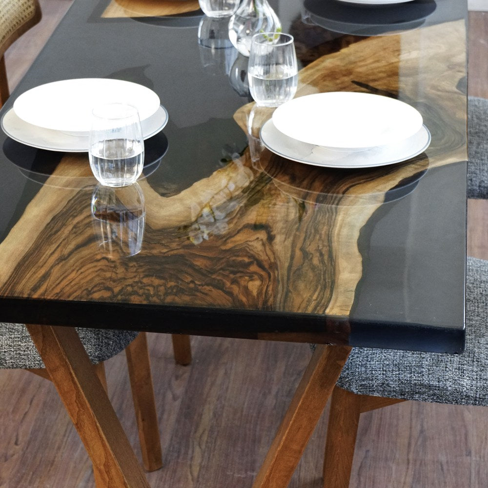 Close-up of the live edge walnut slab and black epoxy river on the dining table top with plates