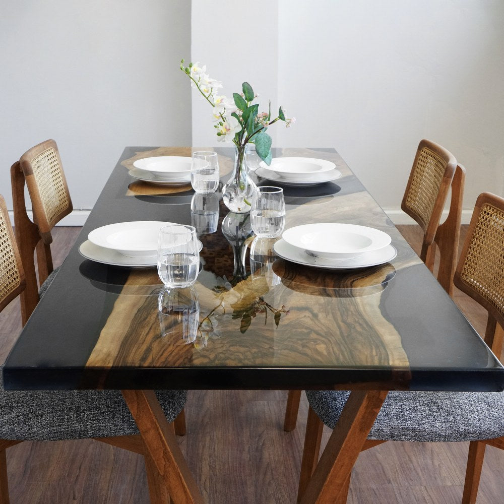 Top-front view of the walnut live edge island in the black epoxy river with a place setting and chairs