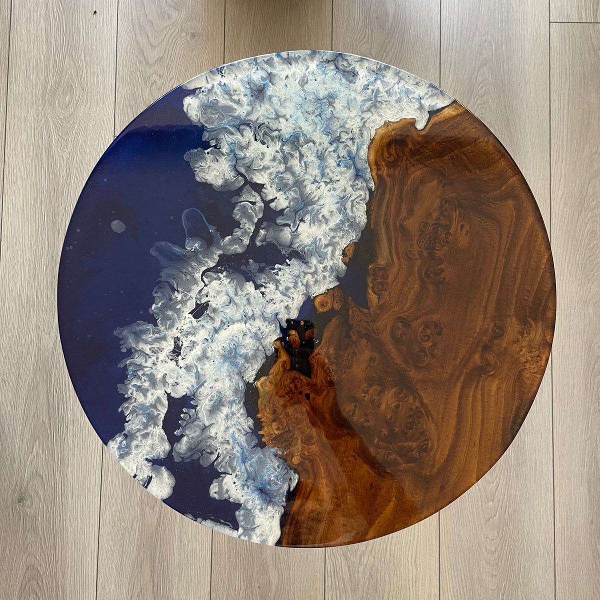 Top-down close-up of the oleaster table's burl wood and ocean blue epoxy with white wave foam