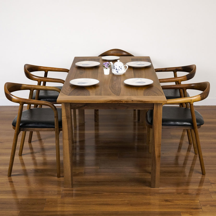 Noren Parsons solid walnut farmhouse dining table, front view with four armchairs and a place setting