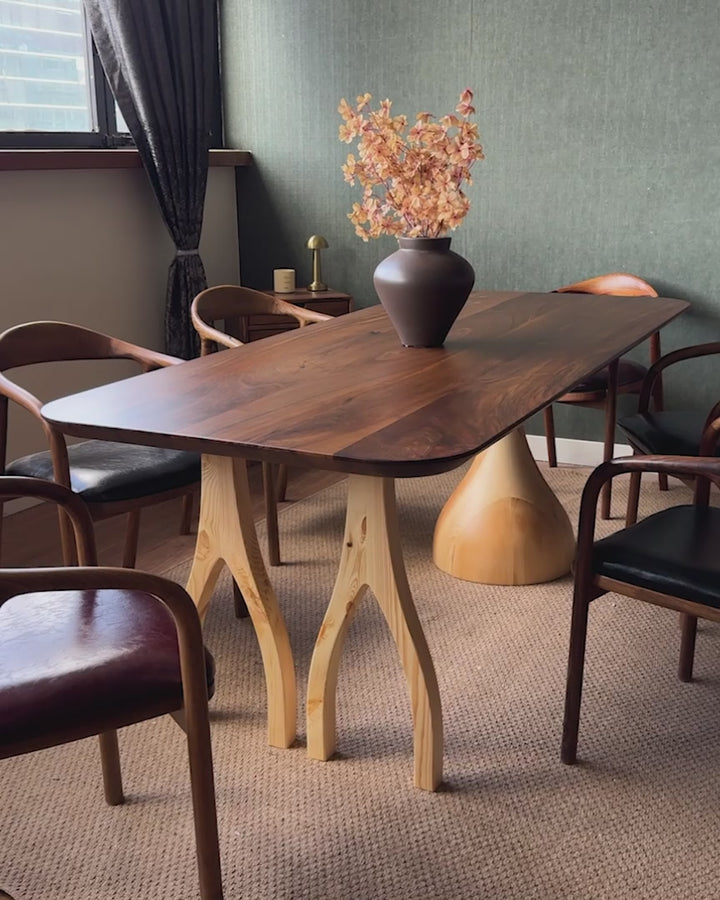 Sculptural dining table — solid walnut top with handcrafted linden wood legs in organic forms