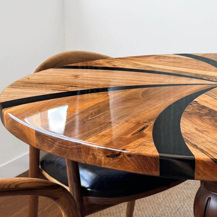 The epoxy-topped dining table with a propeller pattern, rising on a sculptural turned leg, is paired with modern chairs around it.