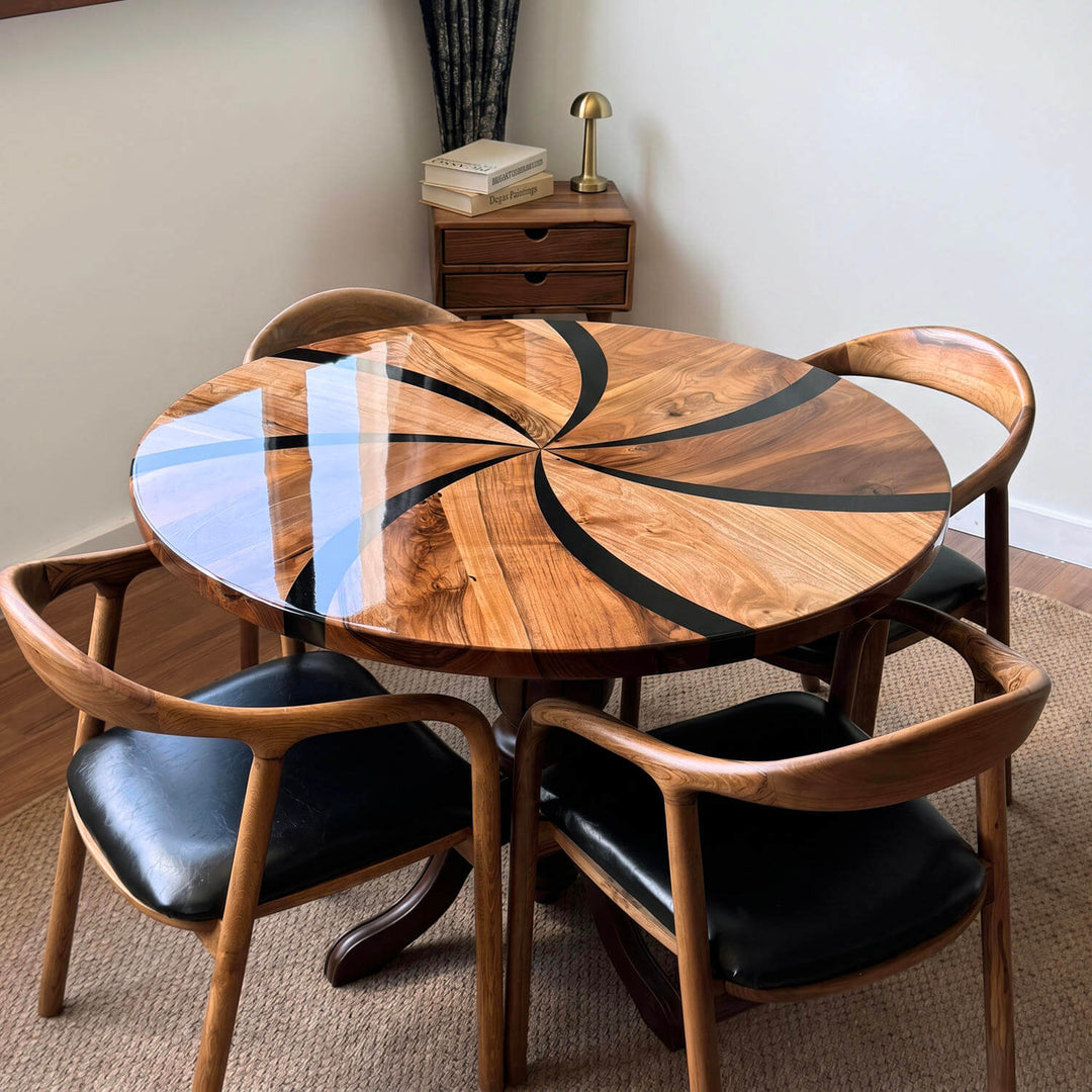 The round dining table, featuring a dynamic propeller-patterned epoxy craftsmanship on its tabletop, stands out with its powerful central turned leg design.