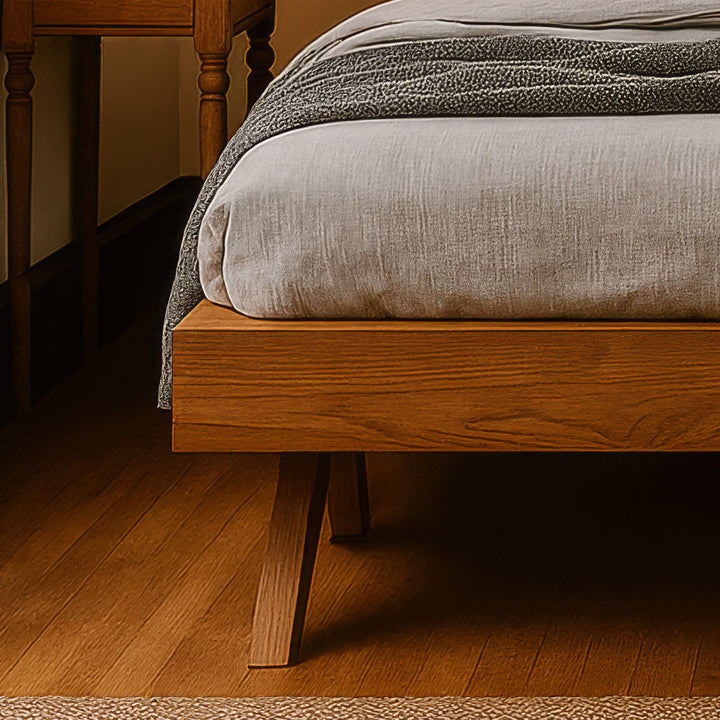 A Scandinavian bed frame adorned with a blanket, accompanied by a nightstand, showcasing a modern bedroom aesthetic.
